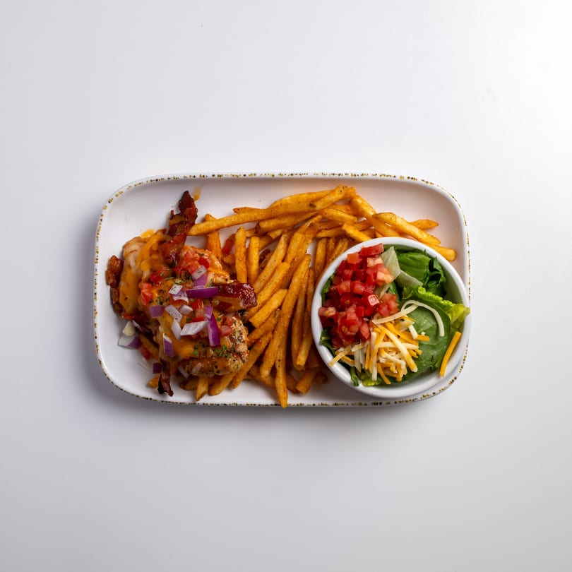 Chicken with melted cheese, bacon, and diced vegetables, served with fries and a side salad.